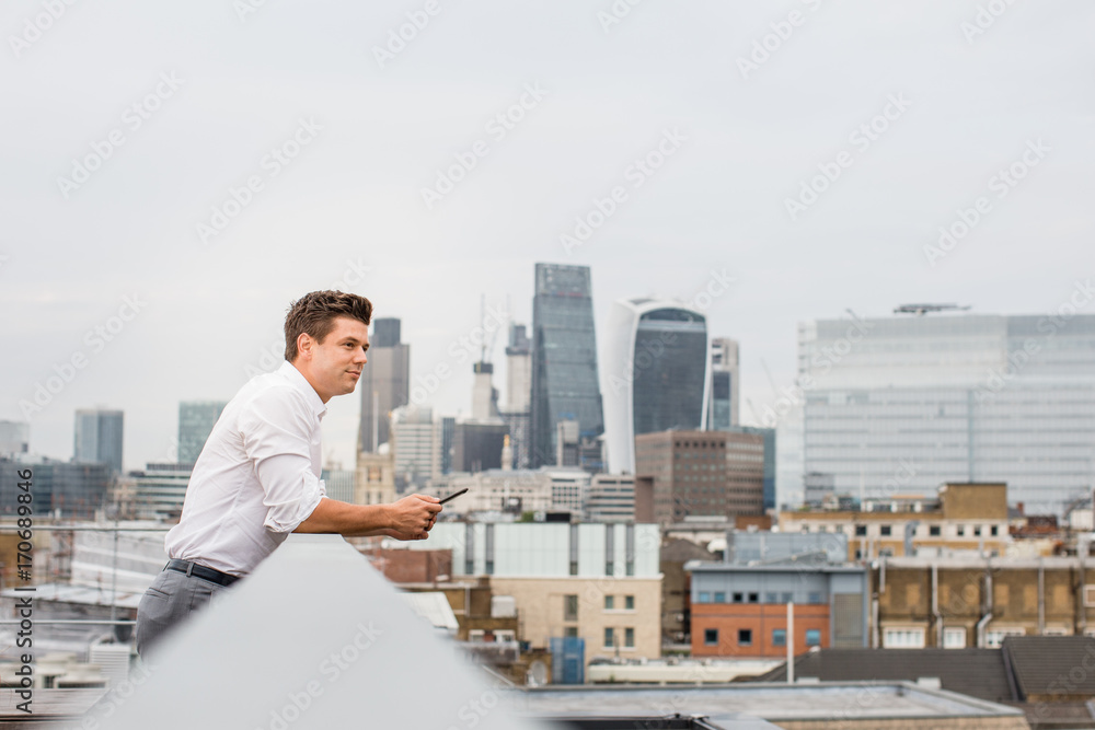 Businessman looking out at London city skyline Businessman looking out at London city skyline