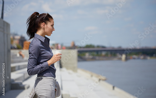 Young businesswoman having a coffee break outdoors on the bridge