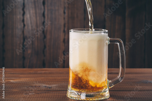 Craft beer poured into a pint glass on the wooden background photo