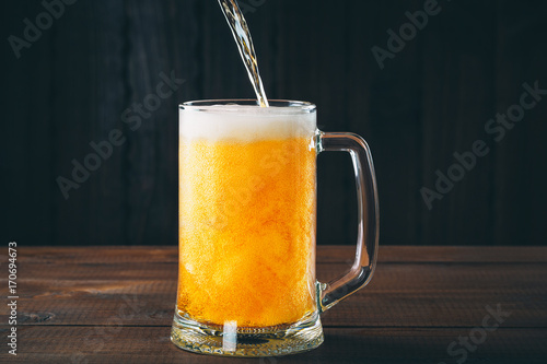 Craft beer poured into a pint glass on the wooden background