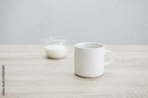WHITE COFFEE CUP WITH MILK JAR  White coffee cup with transparent milk jar on the wood table.   