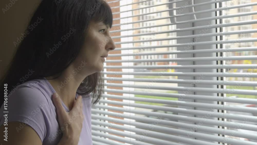 A young beautiful woman stands near a window and coughs. A cold girl has an attack of cough at home. Allergies, colds, bronchitis, asthma. A young beautiful woman stands near a window and coughs. A cold girl has an attack of cough at home. Allergies, colds, bronchitis, asthma.