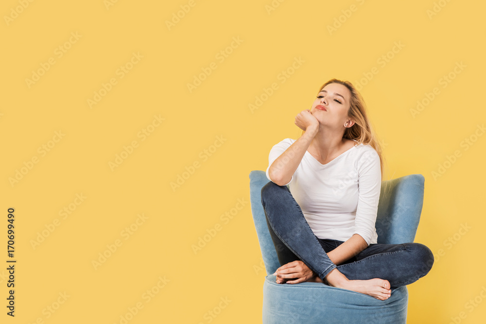 Young blonde woman on chair is bored. Picture includes copy space Young blonde woman on chair is bored. Picture includes copy space
