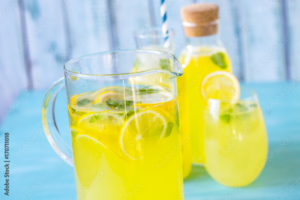 Fototapeta premium fresh lemonade with ice and mint on a blue background