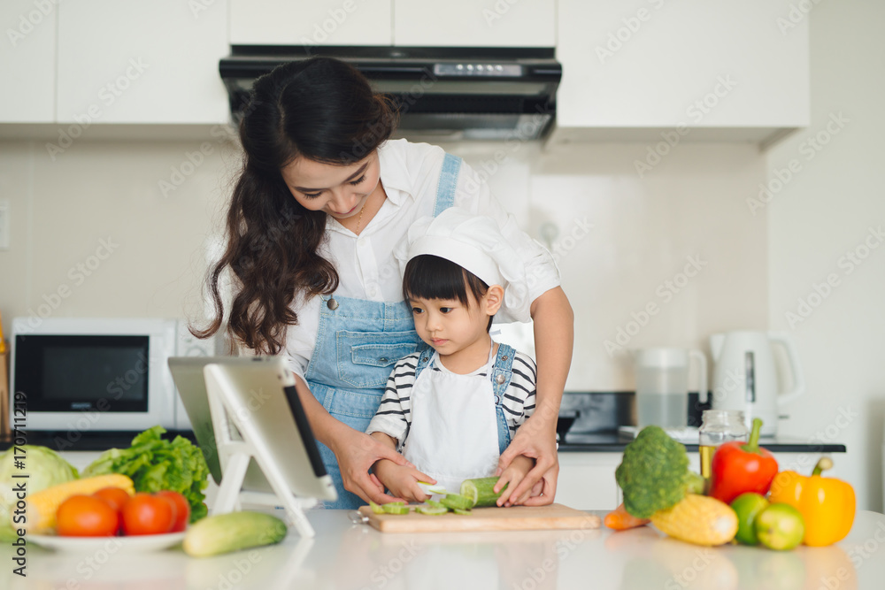 Mother with her daughter in the kitchen cooking together