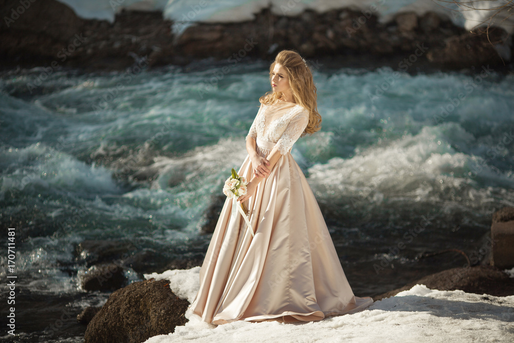 Beautiful young girl in a chic dress in the nature next to the river Beautiful young girl in a chic dress in the nature next to the river