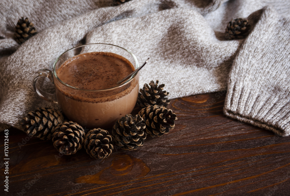 Autumn lifestyle - hot chocolate on tray, warm sweater, candle and cones, rustic wood background Autumn lifestyle - hot chocolate on tray, warm sweater, candle and cones, rustic wood background