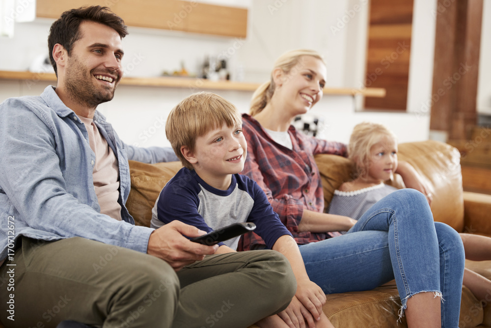 Family Sitting On Sofa In Open Plan Lounge Watching Television Family Sitting On Sofa In Open Plan Lounge Watching Television