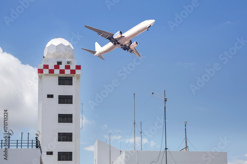 Aeronautical meteorological station tower or weather radar dome station tower in airport with passenger airplane jet taking off on blue sky background © Soonthorn