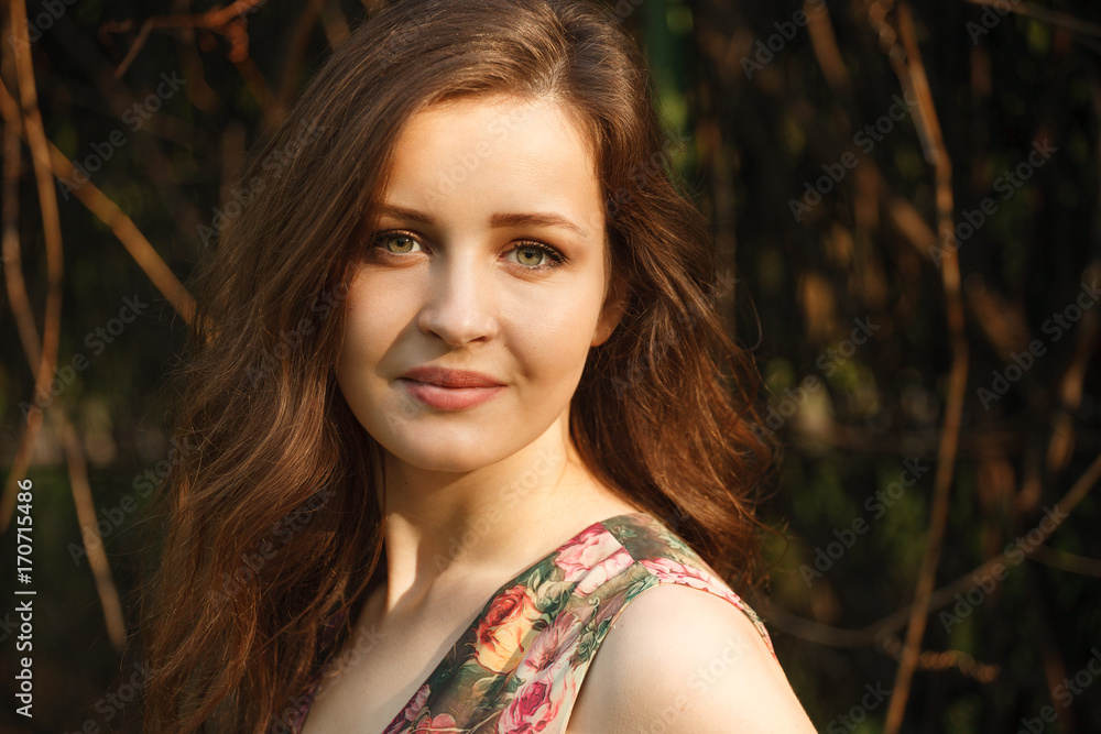 Portait of a young beautiful woman with green eyes and long hair in the sunlight