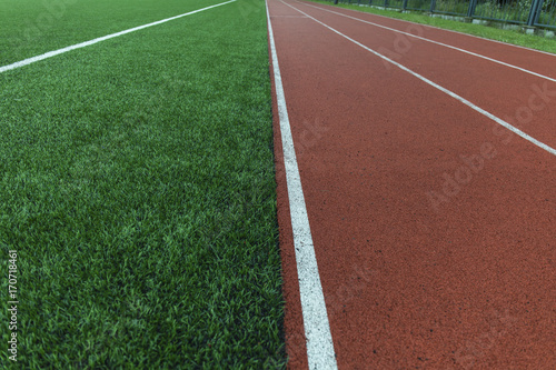 Running track and green grass field stadium