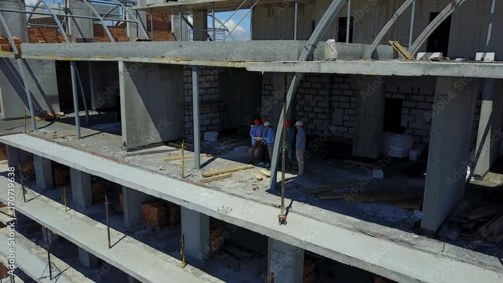 Aerial Shot Of Builders Team On Construction Site Discussing Plan Of Project With Architect And Contractor Using Blueprint On Digital Tablet Aerial Shot Of Builders Team On Construction Site Discussing Plan Of Project With Architect And Contractor Using Blueprint On Digital Tablet