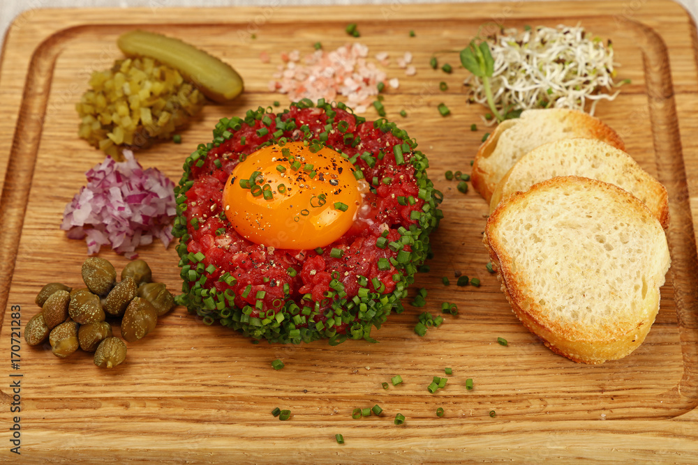 Raw meat tartare steak with egg yolk close up