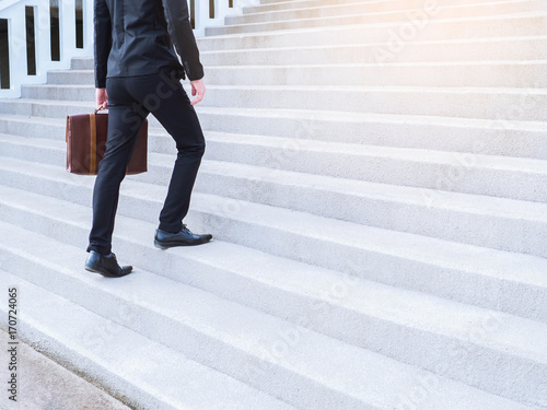 Billede på lærred Businessman legs walking up an outdoor stone staircase