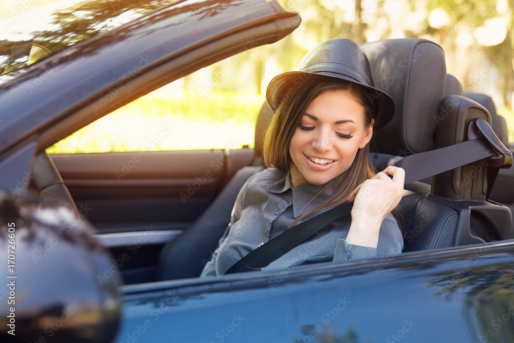 Young woman pulling on seat belt inside black car. Life-saving measures Young woman pulling on seat belt inside black car. Life-saving measures
