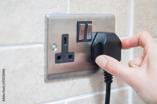 Hand Putting Plug Into Electricity Socket photo