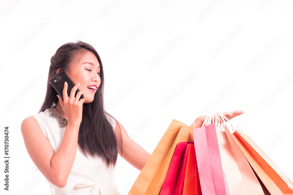 Cheerful shopping woman of Asian holding bags. Shopping smart business woman happy smiling holding colorful shopping bags with smart phone isolated on white . Fresh young Asian female model Cheerful shopping woman of Asian holding bags. Shopping smart business woman happy smiling holding colorful shopping bags with smart phone isolated on white . Fresh young Asian female model