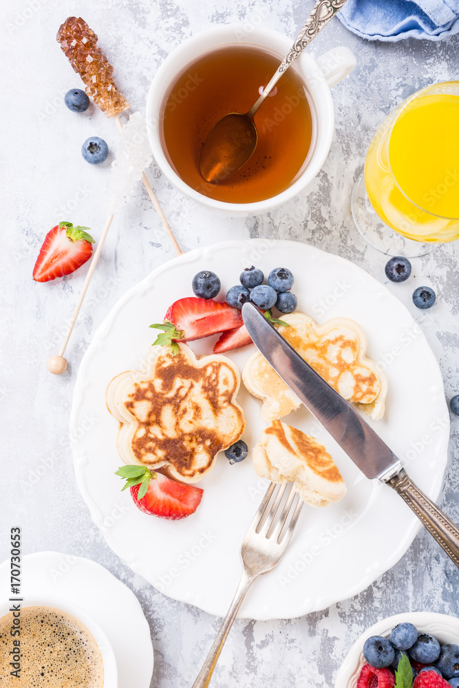 Flat lay with breakfast with scotch pancakes in flower form, berries and honey on light wooden table. Healthy food concept. Flat lay with breakfast with scotch pancakes in flower form, berries and honey on light wooden table. Healthy food concept.