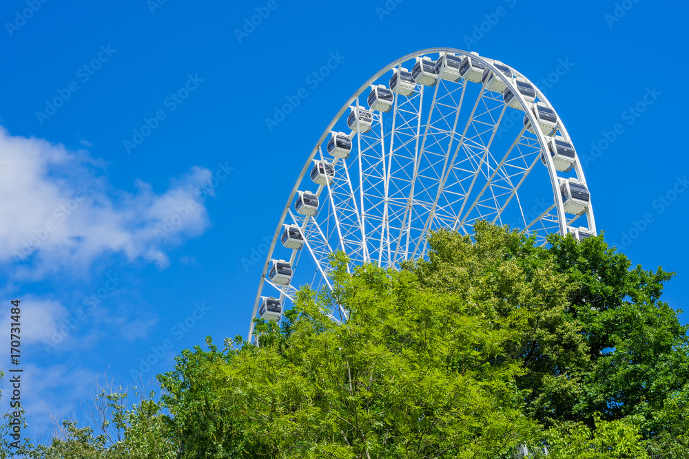 Fototapeta premium Ferris wheel in the amusement park with blue sky at the background