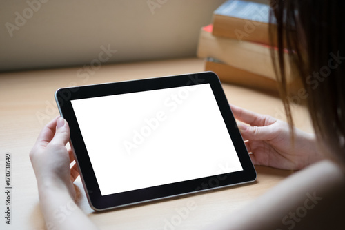 white screen tablet on wooden table with old book