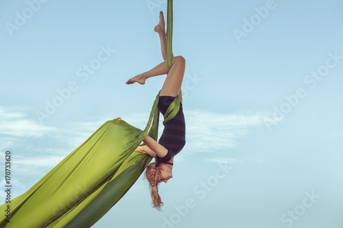 Woman the equilibrist flies in the sky on a hammock.