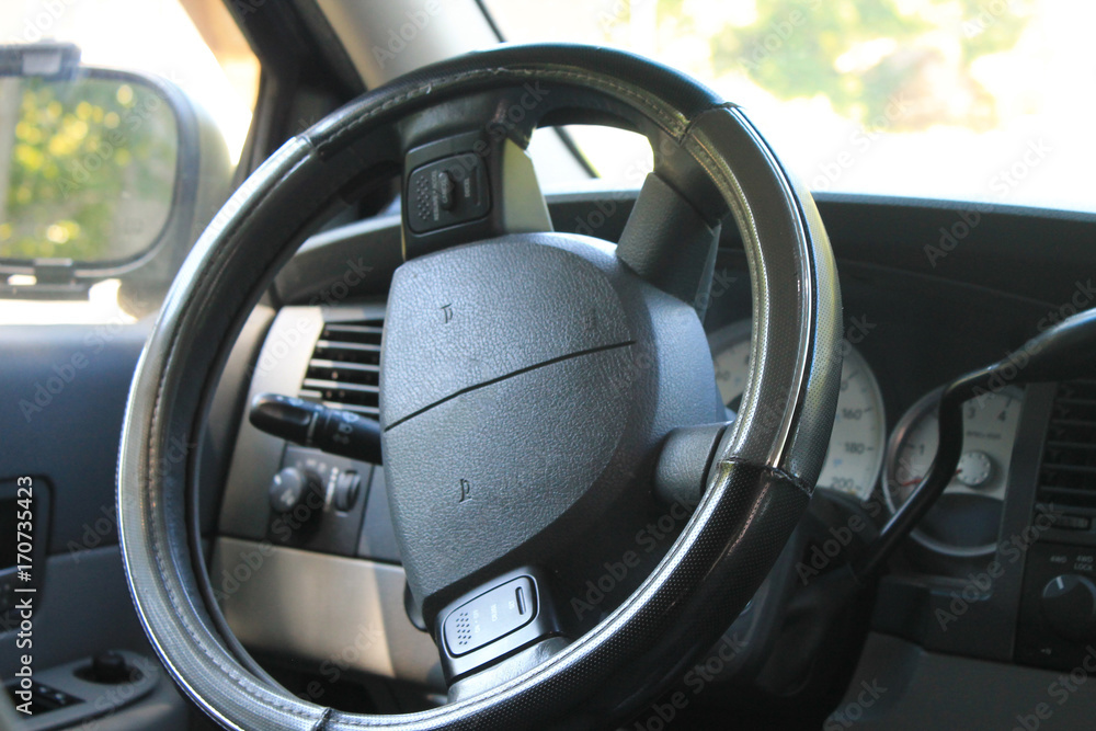 A all black steering wheel with a half turn left parked in a forest