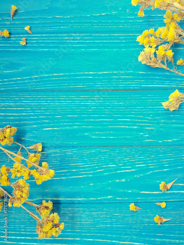 Dry yellow flowers forming a frame on a vintage wooden background, retro style (with copy space in the center for your text)