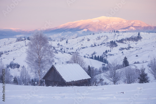 Snowy mountain hills with wooden cabin © Nickolay Khoroshkov