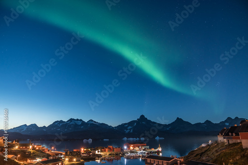 Seaside village with green aurora at twilight on the coast of Greenland photo