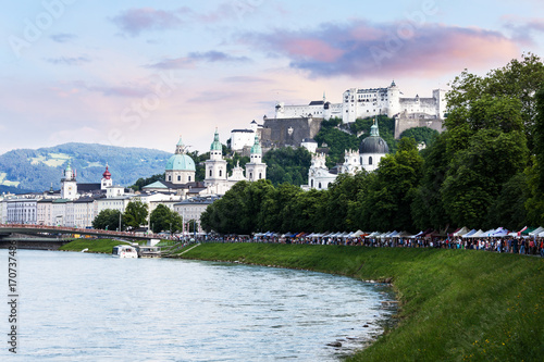 Tourists walking along river bank in historical city center of Salzburg