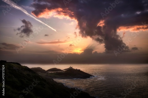 Sunrise, contrails and a mushroom style cloud over Mumbles lighthouse, Swansea, South Wales, UK photo