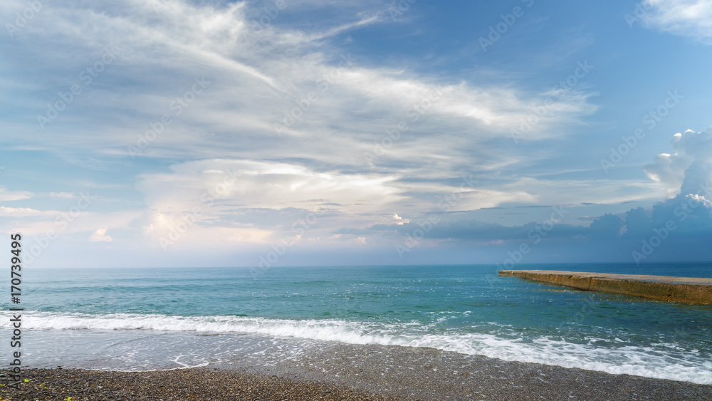 calm black sea pebble beach / turquoise water on the beach on the background of stratus clouds