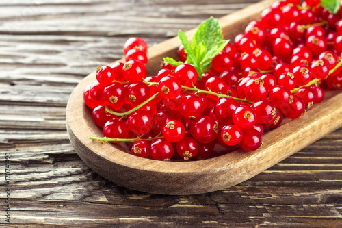 Canvas Print Ripe redcurrants in a wooden plate on a wooden background.