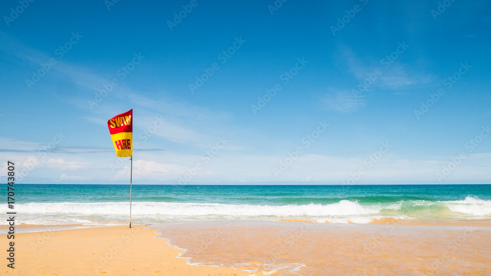 A word Swin Here on the red and yellow flags on the beach.To tell the point safe for swimming In security concept.