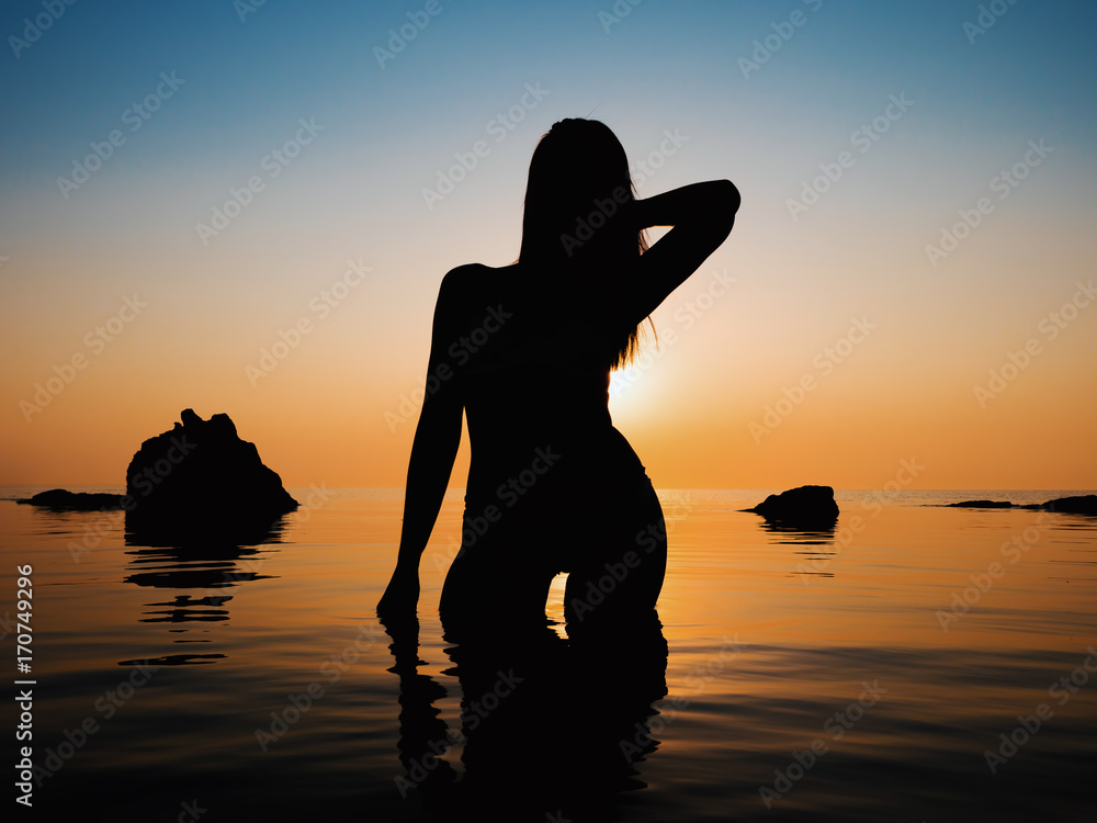 Sunset, sexy woman silhouette. Vacation, sillhouette of traveling girl in  bikini standing in sea at sunrise or sunset. Lady with slim sexy body on  tropical beach. Luxury destination Stock Photo | Adobe