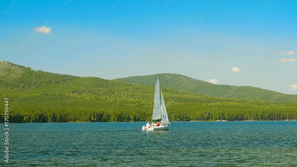 Fototapeta premium Sailboat on the water. Sailboats on the beautiful Lake of the. White sailboat floating on the lake