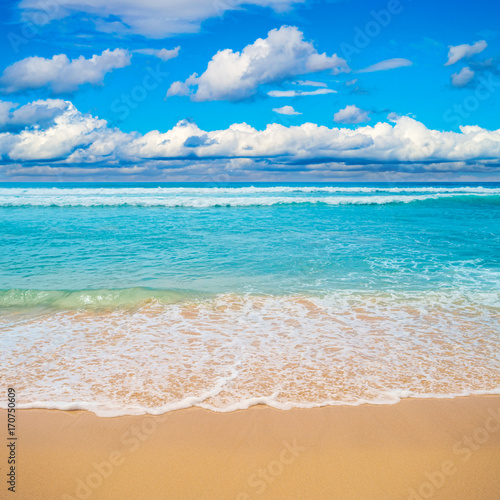 Sea waves white foam over golden beach sand