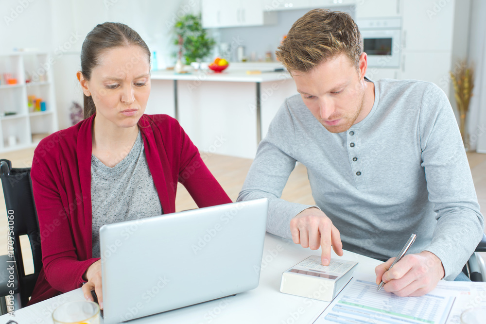 young couple calculating their expenses and incomes young couple calculating their expenses and incomes