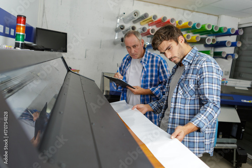 two men looking down at professional printer