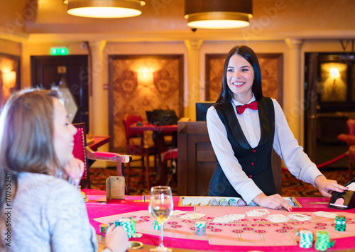Cute lady casino dealer at poker table. Player is playing Black Jack.