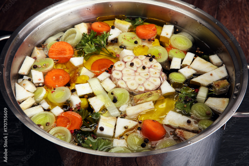 Broth with carrots, onions various fresh vegetables in a pot - colorful fresh clear spring soup. Rural kitchen scenery vegetarian bouillon or stock Broth with carrots, onions various fresh vegetables in a pot - colorful fresh clear spring soup. Rural kitchen scenery vegetarian bouillon or stock