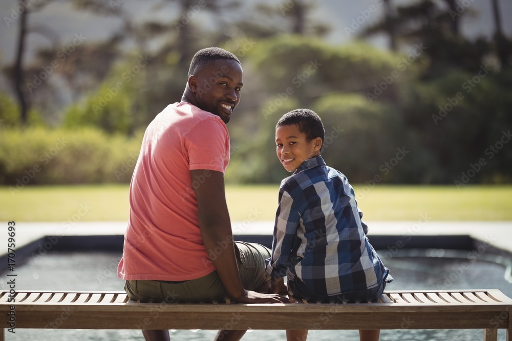 Smiling father and son sitting together on bench
