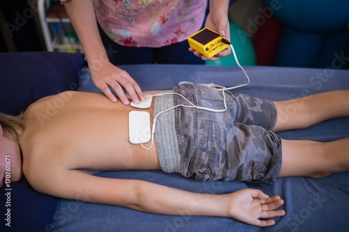 Fotografía High angle view of female therapist placing electrodes on back