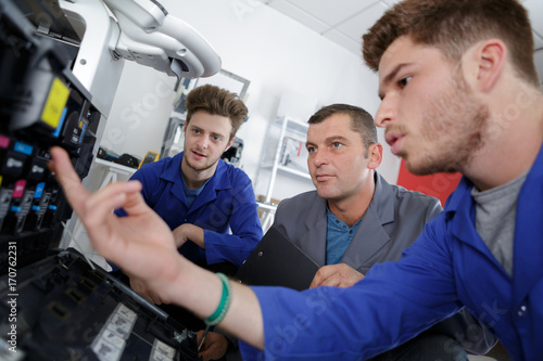 two apprentices and teacher working on printer
