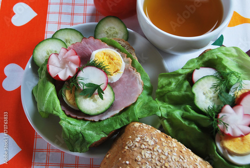 Polish sandwich breakfast with ham cucumber egg radish dill lettuce and hot tea