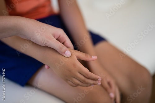 Close-up of female therapist examining hand while boy sitting on