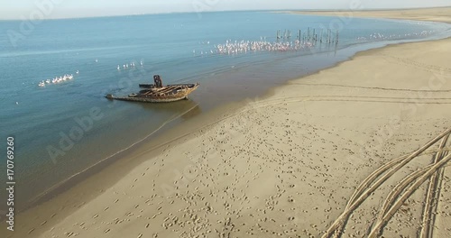 Aerial view drone video of Pelican Point Lodge and Paratus lighthouse on sand beach peninsula, shipwreck and lagoon with ocean background with ships at Namibia's Atlantic west coast