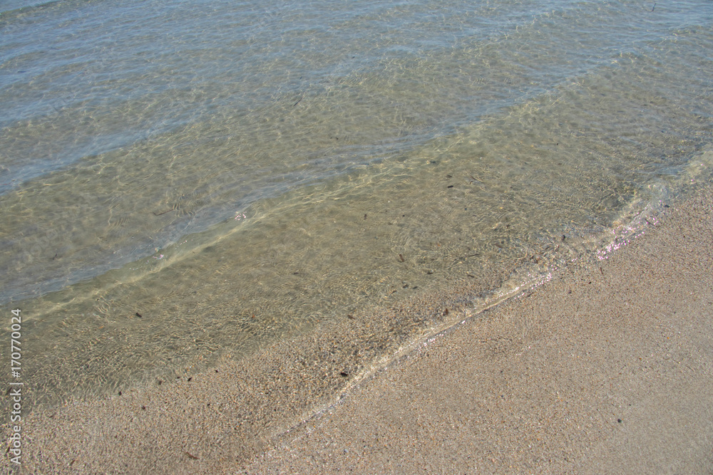 crystal clear water on the shore of a sandy beach on a sunny day crystal clear water on the shore of a sandy beach on a sunny day