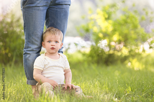 Cute baby boy and mother on green grass in park