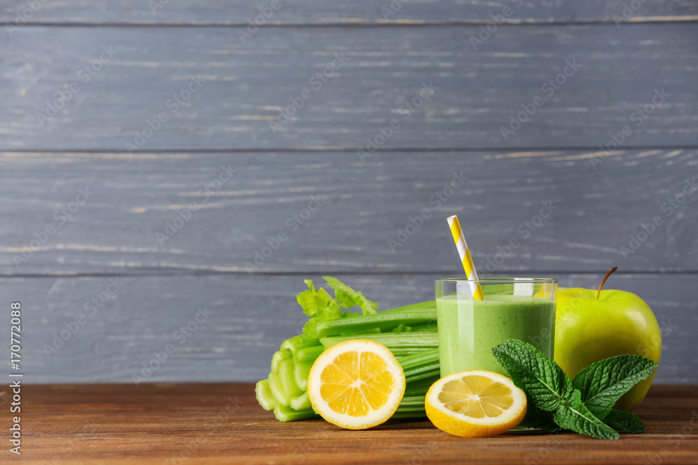 Fototapeta premium Glass of green healthy juice with ingredients on wooden table